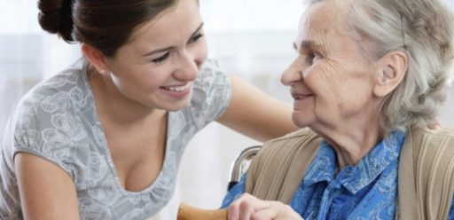 A women smiling at an elderly lady in a wheel chair