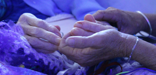 Two hands supporting an elderly person