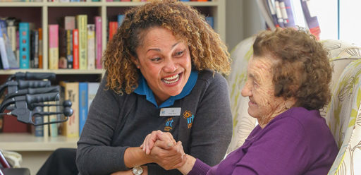 Aged care working holding hands with elderly woman