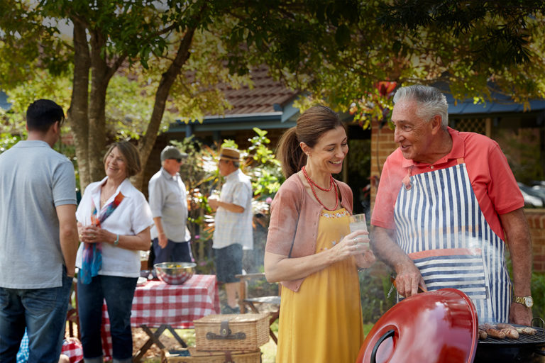 A group of men and women enjoying a BBQ in the retirement village backyard - Retirement Living Council Campaign