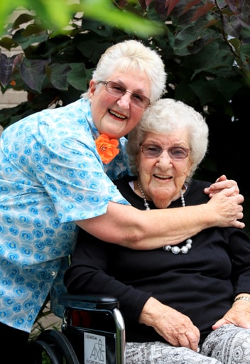 A woman hugging a another woman in a wheelchair