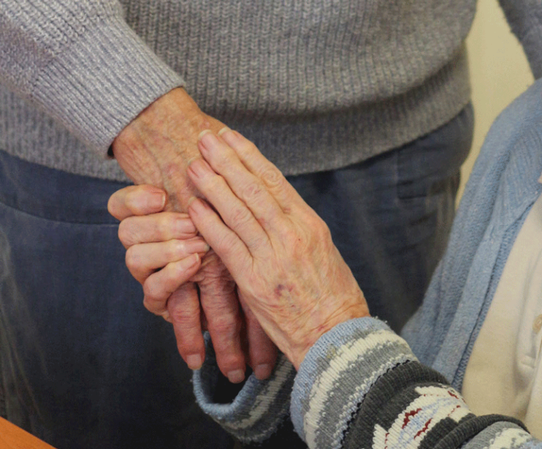 Supportive hands comforting an elderly person